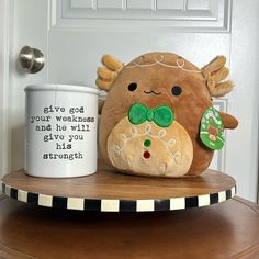 a stuffed animal sitting next to a coffee mug on a wooden table in front of a door