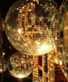 disco balls are hanging from the ceiling in front of a mirror ball sculpture at night