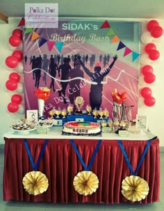 a red table topped with lots of desserts and balloons in front of a poster