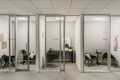 an office cubicle with glass walls and chairs