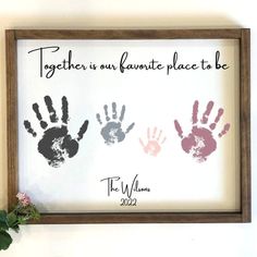 two hand prints in a wooden frame with the words together is our favorite place to be