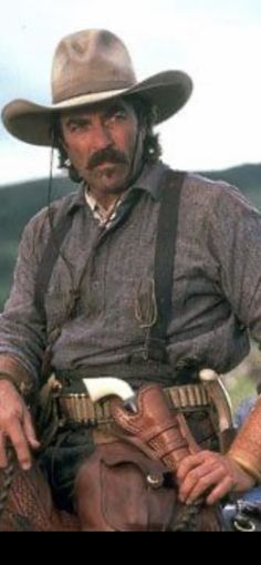 a man wearing a cowboy hat sitting on top of a motorcycle