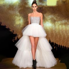 a model walks down the runway in a white dress