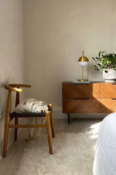 a bed room with a neatly made bed and a wooden chair next to a dresser