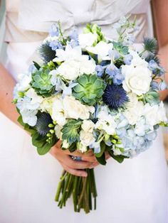 a bride holding a bouquet of white and blue flowers