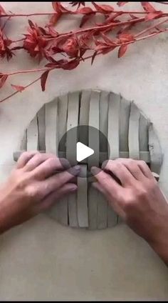 two hands are working on a piece of art that is made out of wood and cement