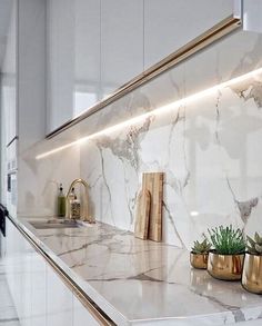 a kitchen with marble counter tops and gold vases on the countertop next to it