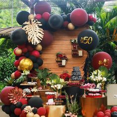 a table topped with lots of balloons and other decorations in front of a wooden wall