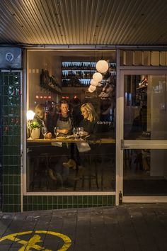 three people sitting at a table in front of a store window