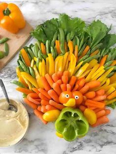 a turkey made out of carrots and peppers on a counter with dip in the middle