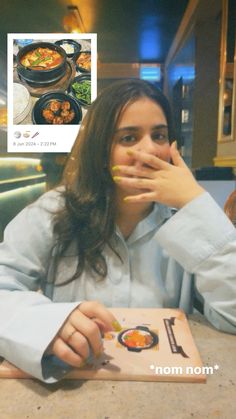 a woman sitting at a table with food in front of her face and an advertisement on the wall behind her