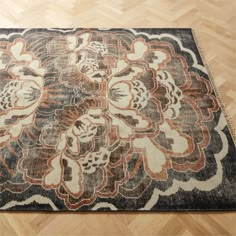 a large rug with an intricate design on top of wood flooring in a room