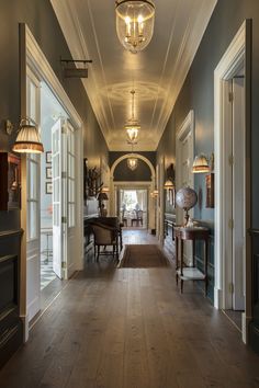 a long hallway with wooden floors and chandeliers on either side of the hall