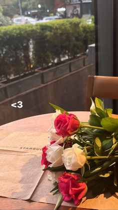 flowers are sitting on the table in front of an open window overlooking a city street