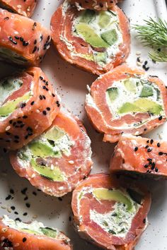 several pieces of sushi on a white plate with black sesame sprinkles