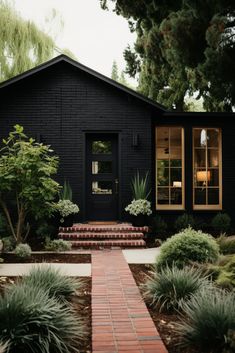 a black house with steps leading up to the front door and entry way, surrounded by greenery