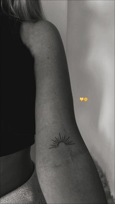 a black and white photo of a woman's arm with a sun tattoo on it