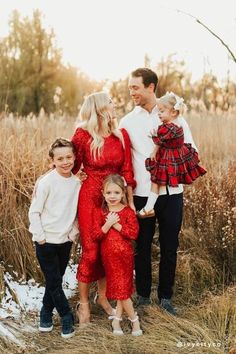 a family posing for a photo in front of some tall grass and trees with snow on the ground