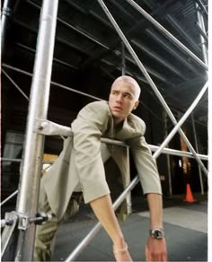 a man leaning against a metal structure with his hand on the railing and looking at the camera