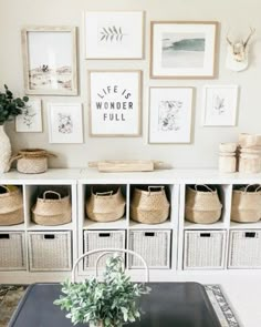 a dining room table with baskets on it and pictures hanging above the table in front of it