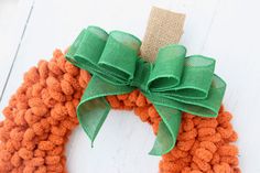 an orange and green knitted wreath with a bow