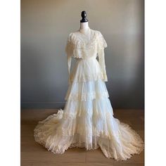 a white wedding dress on a mannequin with long sleeves and tiered layers