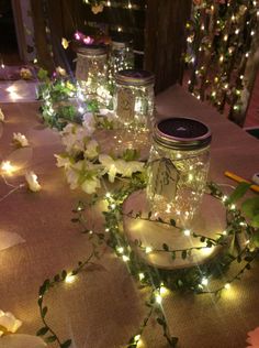 mason jars with lights and greenery on a table