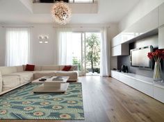 a living room with white walls and flooring has a chandelier hanging from the ceiling