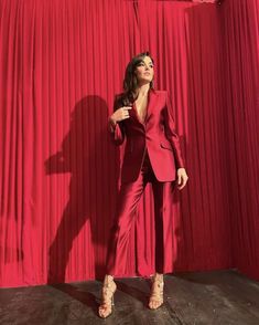 a woman standing in front of a red curtain with her hands on her hips and looking up