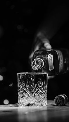 a person pouring water into a glass on top of a table