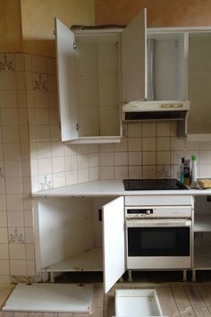 an empty kitchen with white cupboards and appliances on the floor in front of it