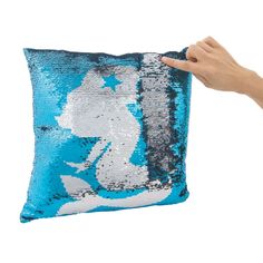 a hand holding a blue and white sequin pillow