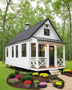 a small white house surrounded by flowers and trees