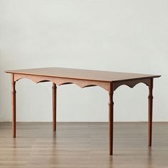 a wooden table sitting on top of a hard wood floor next to a white wall