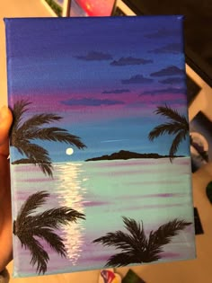 someone is holding up a painting with palm trees and the moon in the sky behind them