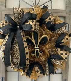 a black and gold mask hanging from the side of a door with ribbon around it