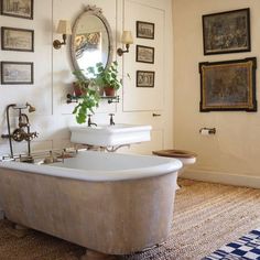 an old fashioned bathtub in a bathroom with pictures on the wall