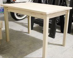 a wooden table sitting on top of a floor next to a motor scooter