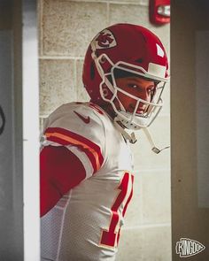 a man in a football uniform standing next to a brick wall and wearing a helmet