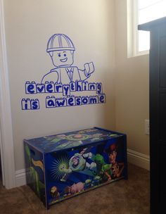 a toy chest sitting in front of a wall with the words everything is awesome on it