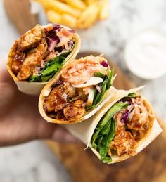 two wraps filled with meat and veggies on top of a cutting board