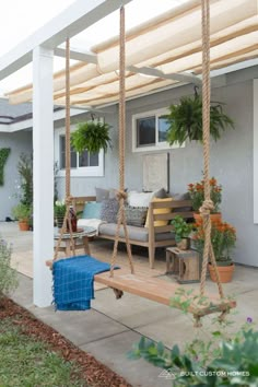 a porch swing that is attached to the side of a house with potted plants on it