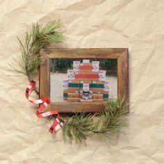 an old wooden frame with christmas decorations and ribbon around it on a piece of paper