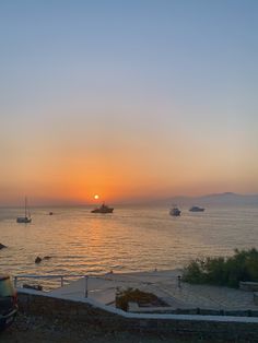 the sun is setting over some boats in the water