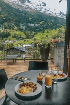 a table with two plates of food and drinks on it in front of a mountain view