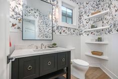 a bathroom with a toilet, sink and shelves in the wall next to the mirror