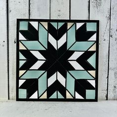 a black and white tile with an arrow design on the side of a wooden wall