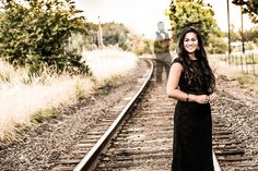 a woman standing on train tracks with her arms crossed in front of her face and smiling at the camera