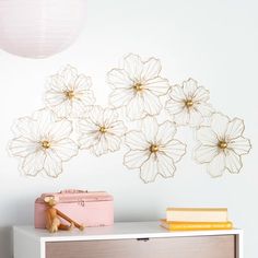 a white dresser topped with a pink chest of drawers next to a wall mounted art piece