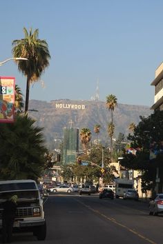 cars are driving down the street in front of hollywood sign